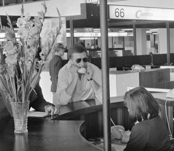 Cuba-gangers wachten op vliegtuig in vertrekhal Schiphol. Schrijver Harry Mulisch.